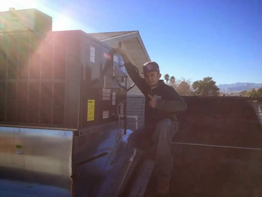 HVAC technician performing Air Duct Cleaning on a rooftop unit in Holladay